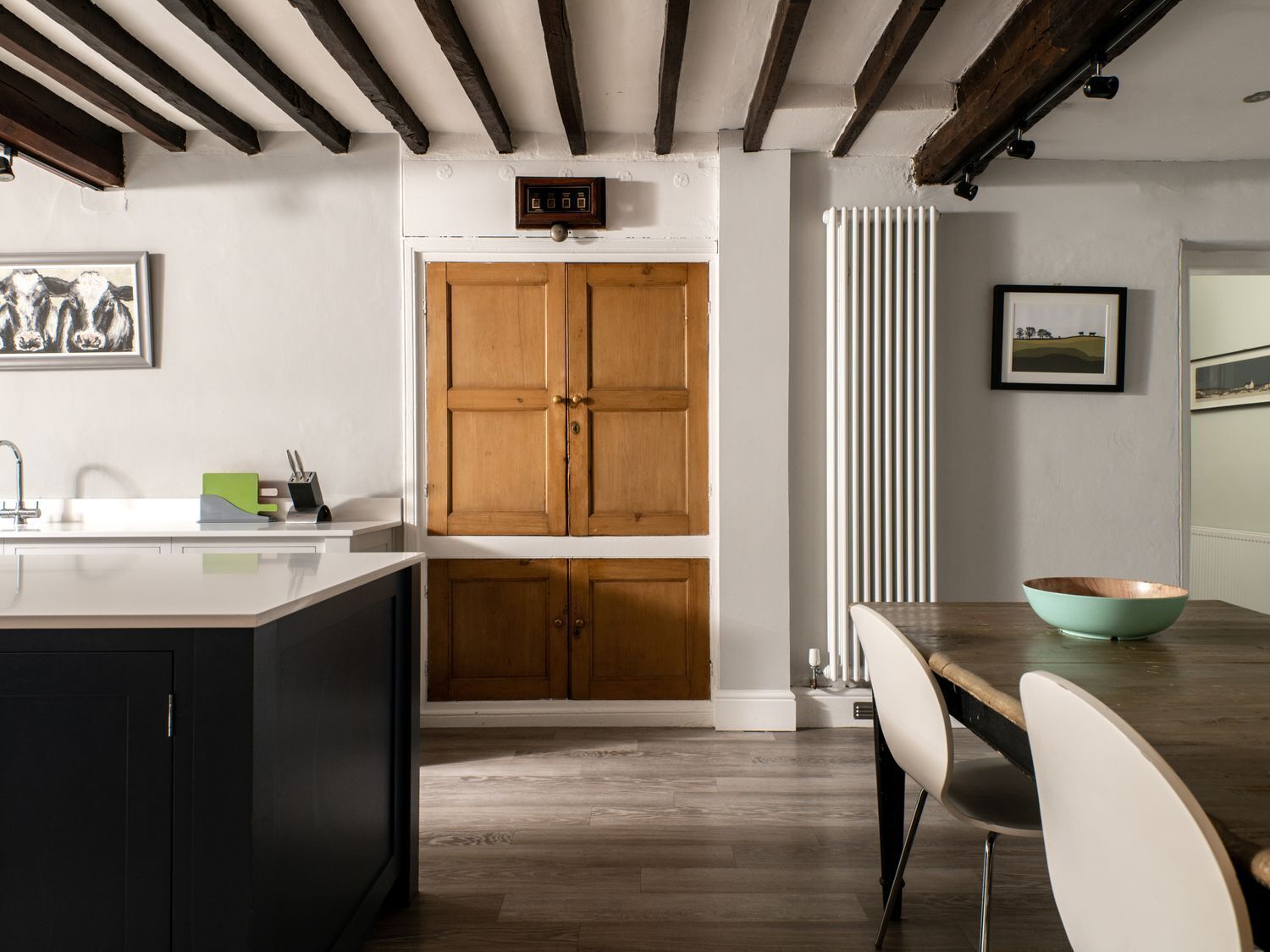 A kitchen with wooden cabinets, a white countertop, and a dining table with chairs.