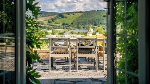 An outdoor dining area with a table set for two, overlooking a scenic landscape with hills and a lake. - Fron Dderw (Bala)