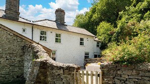 A stone building with a white facade, a wooden gate, and a stone wall. - Fron Dderw (Bala)