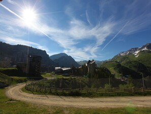 Un paysage montagneux avec un ciel dégagé, un chemin de terre et des bâtiments, dont l’un est identifié par l’inscription « AQUARIAZ ».
