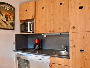 Une cuisine avec des meubles de rangement en bois, un four à micro-ondes, une machine à café et un lave-vaisselle.