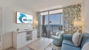 Ein modernes Wohnzimmer mit Flachbildfernseher, Sofa, Couchtisch und einem Balkon mit Blick.