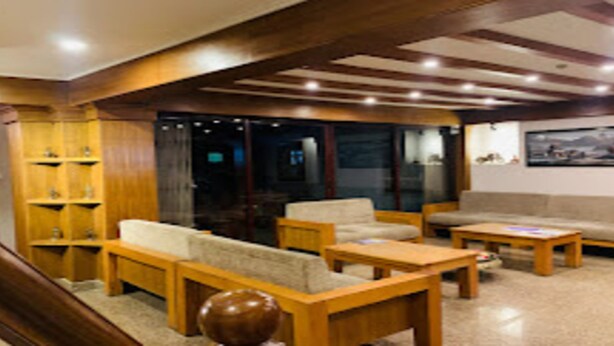 A lobby with wooden furniture, a reception desk, and a wall-mounted painting. - MeroStay 220 Hotel CBR (Bhaktapur)
