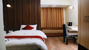 A hotel room with a bed, a desk, a chair, and a wardrobe. - MeroStay 220 Hotel CBR (Bhaktapur)