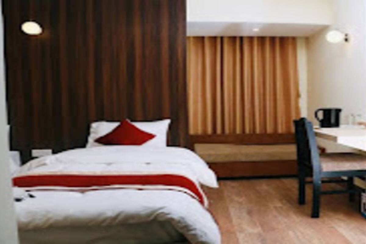 Quarto de hotel com cama, escrivaninha, cadeira e guarda-roupa.