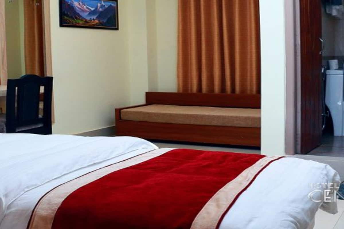 Quarto de hotel com cama, secretária com cadeira, sofá e um quadro na parede.