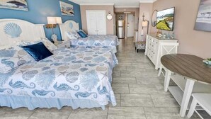 A bedroom with two beds, a wooden bench, a TV, and a dining table.