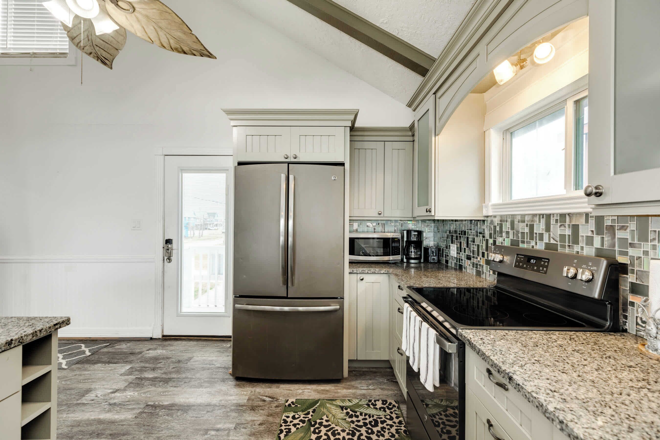 A kitchen with a stainless steel refrigerator, a microwave, a stove, and a tiled backsplash.