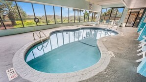 Ein Hallenbad mit freiem Blick auf Palmen und eine Wüstenlandschaft durch große Fenster.
