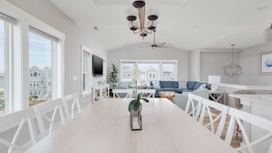 Un comedor amplio con una mesa larga, sillas blancas y un candelabro.