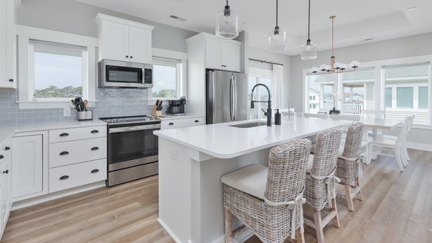 Una cocina moderna con armarios blancos, electrodomésticos de acero inoxidable y una isla grande con taburetes de bar.