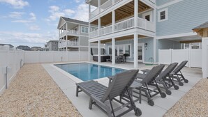 Un área de piscina con sillones de descanso y una terraza cubierta.