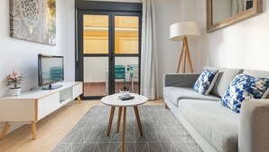 A modern living room with a sofa, a coffee table, a TV, and a decorative wall piece. - Holiday Rentals Tempa Museo (Seville)