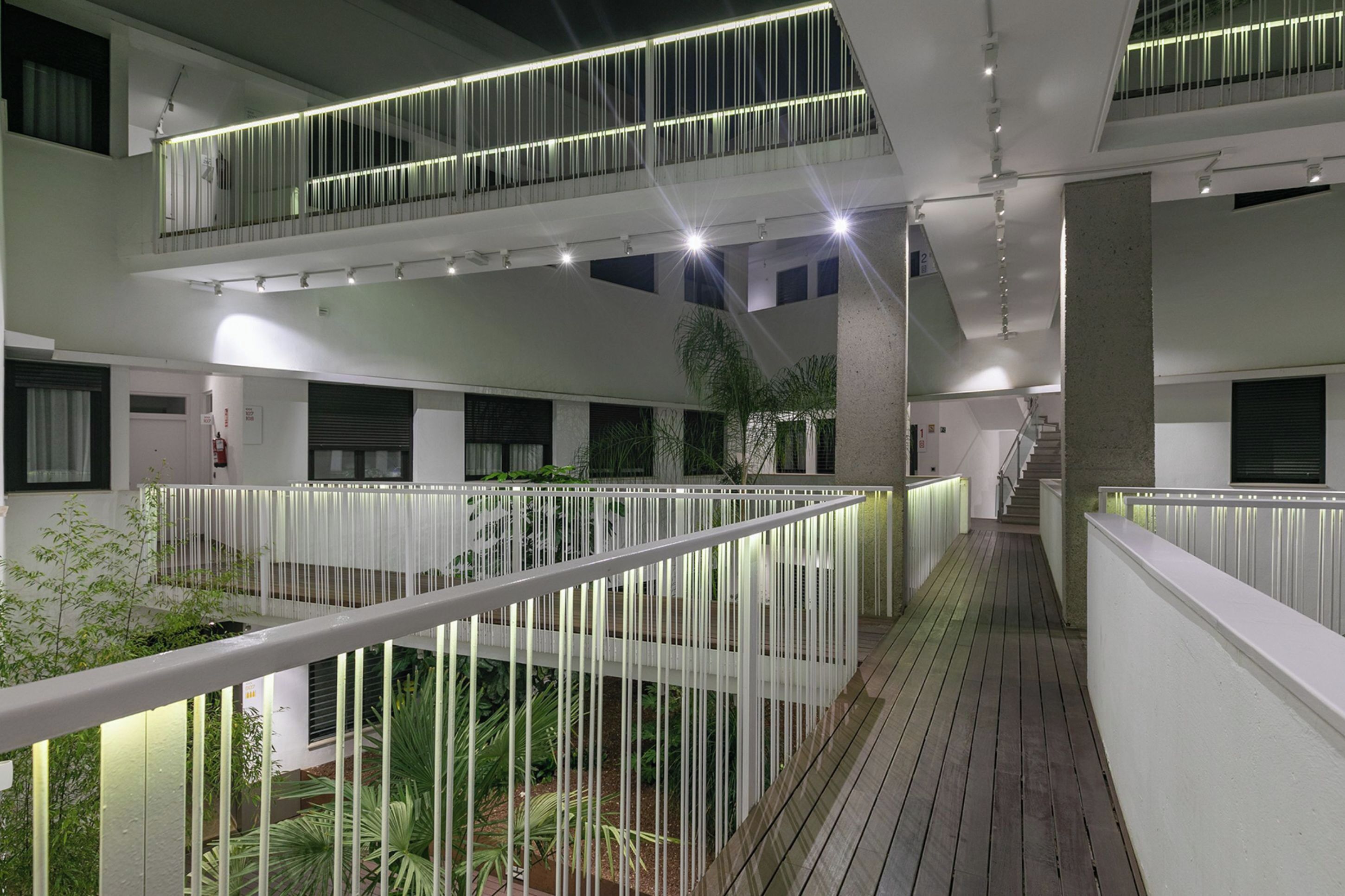 A multi-level indoor space with balconies, wooden flooring, and artificial lighting.