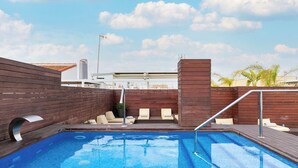 A rooftop swimming pool with wooden deck, lounge chairs, and a view of the city skyline. - Holiday Rentals Tempa Museo (Seville)