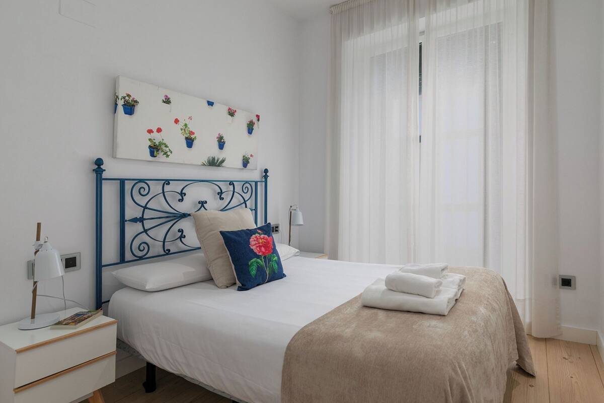 A neatly made bed with a blue headboard, white bedding, and a decorative pillow.