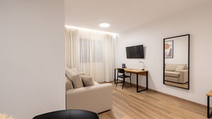 Ein modernes, helles Zimmer mit einer Couch, einem Schreibtisch und einem Stuhl.