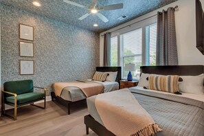 A bedroom with a patterned wallpaper, two beds, a chair, and a ceiling fan. - Luxe Downtown Oasis • Spacious • Private Rooftop (Nashville)