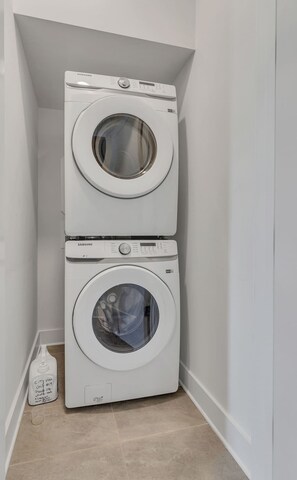 A stacked washer and dryer unit in a corner of a room with white walls and a tiled floor.