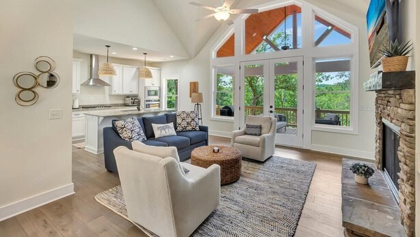 A spacious living area with a high ceiling, a fireplace, and large windows offering a view of the outdoors. - Peninsula Rd - Fun and Relaxation (West Union)