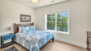 A bedroom with a bed, a nightstand, a dresser, a ceiling fan, and a window with a view of trees. - Peninsula Rd - Fun and Relaxation (West Union)