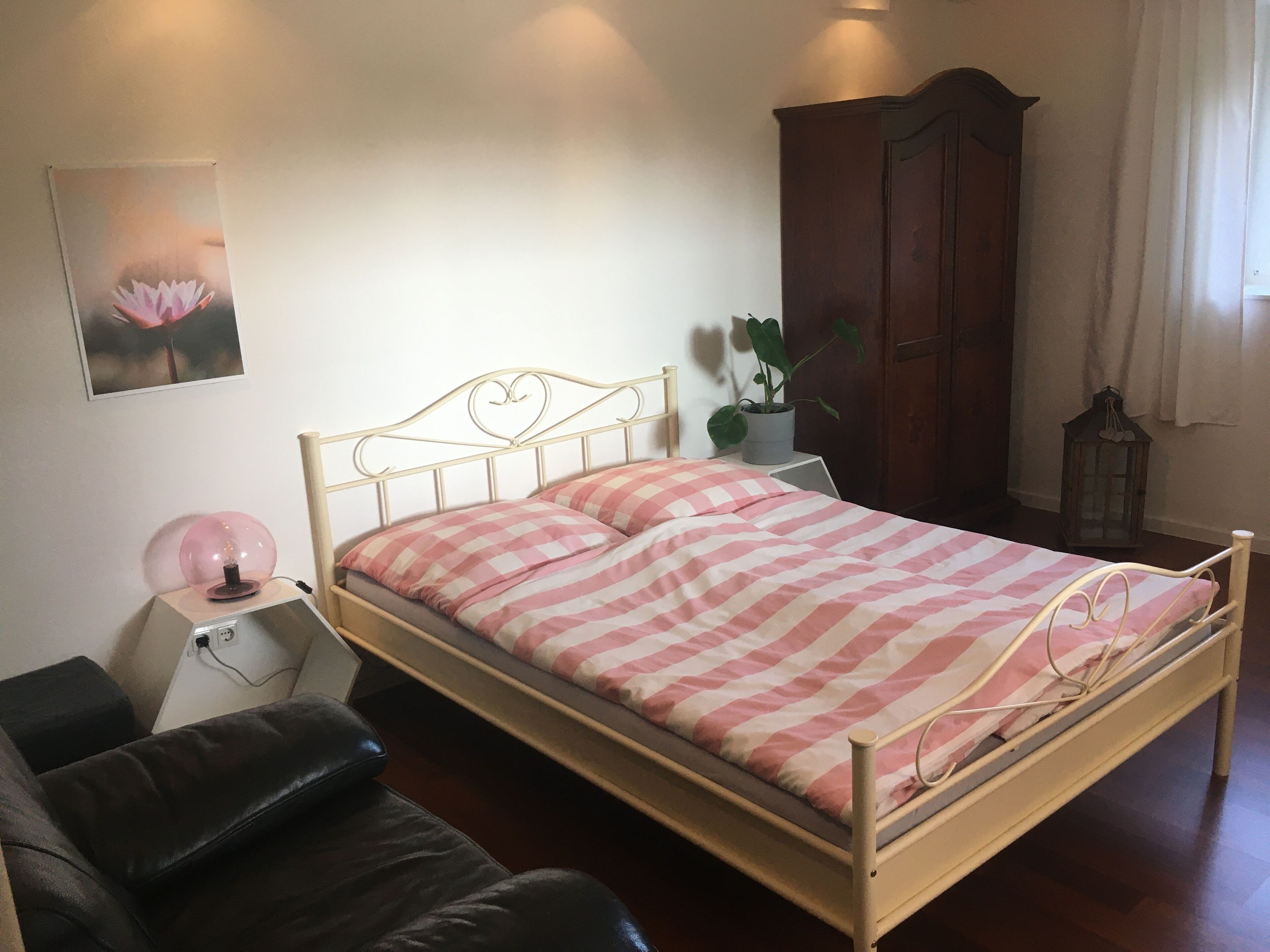 Une chambre à coucher comprenant un lit, un bureau, une chaise, une armoire et une plante en pot.
