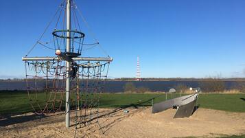 Ein Spielplatz mit einer Kletteranlage und einem Boot im Hintergrund.