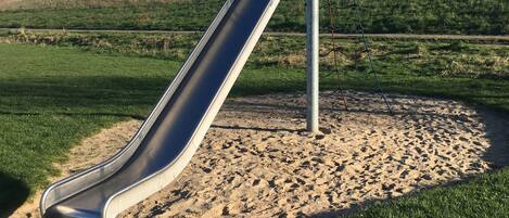 Un parque infantil con un tobogán y un arenero.