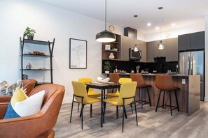 A modern kitchen with a central island, bar stools, and a dining table with chairs. - Summit Place - Condo With Mountain Views (Revelstoke)