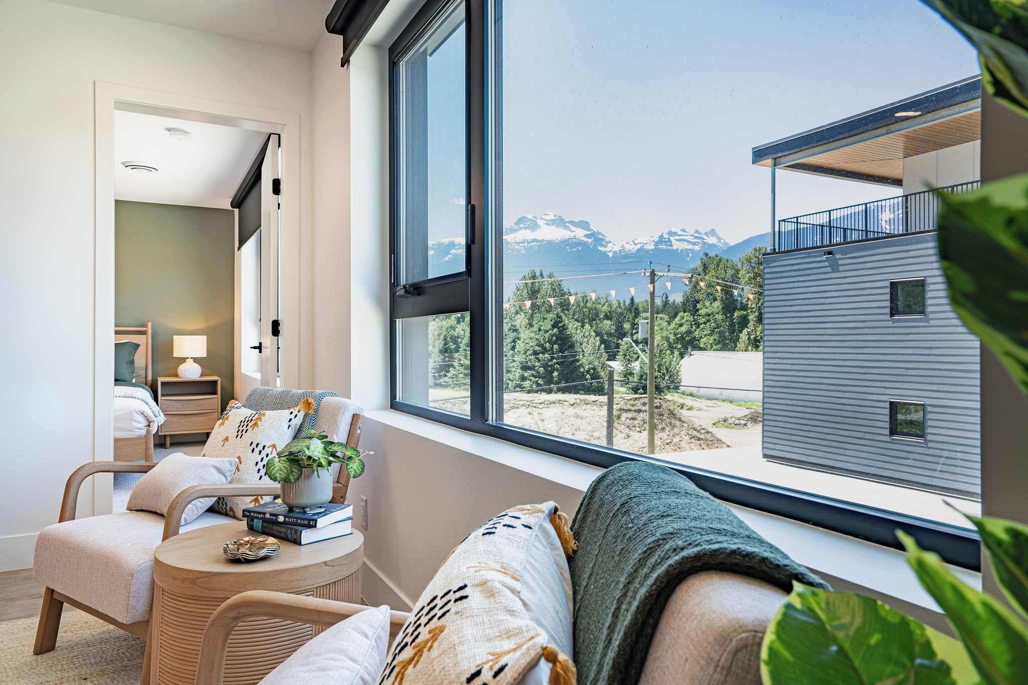 A modern interior with a large window, a cozy seating area, and a view of mountains.