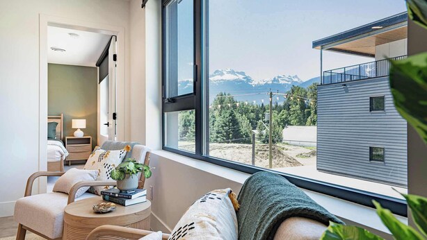 Ein modernes Interieur mit einem großen Fenster, einer gemütlichen Sitzecke und Bergblick.