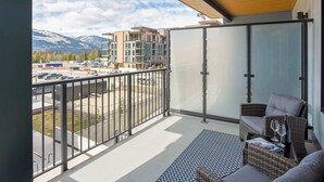 Ein Balkon mit Blick auf Berge, einer Rattan-Sofas und eine Glastür.