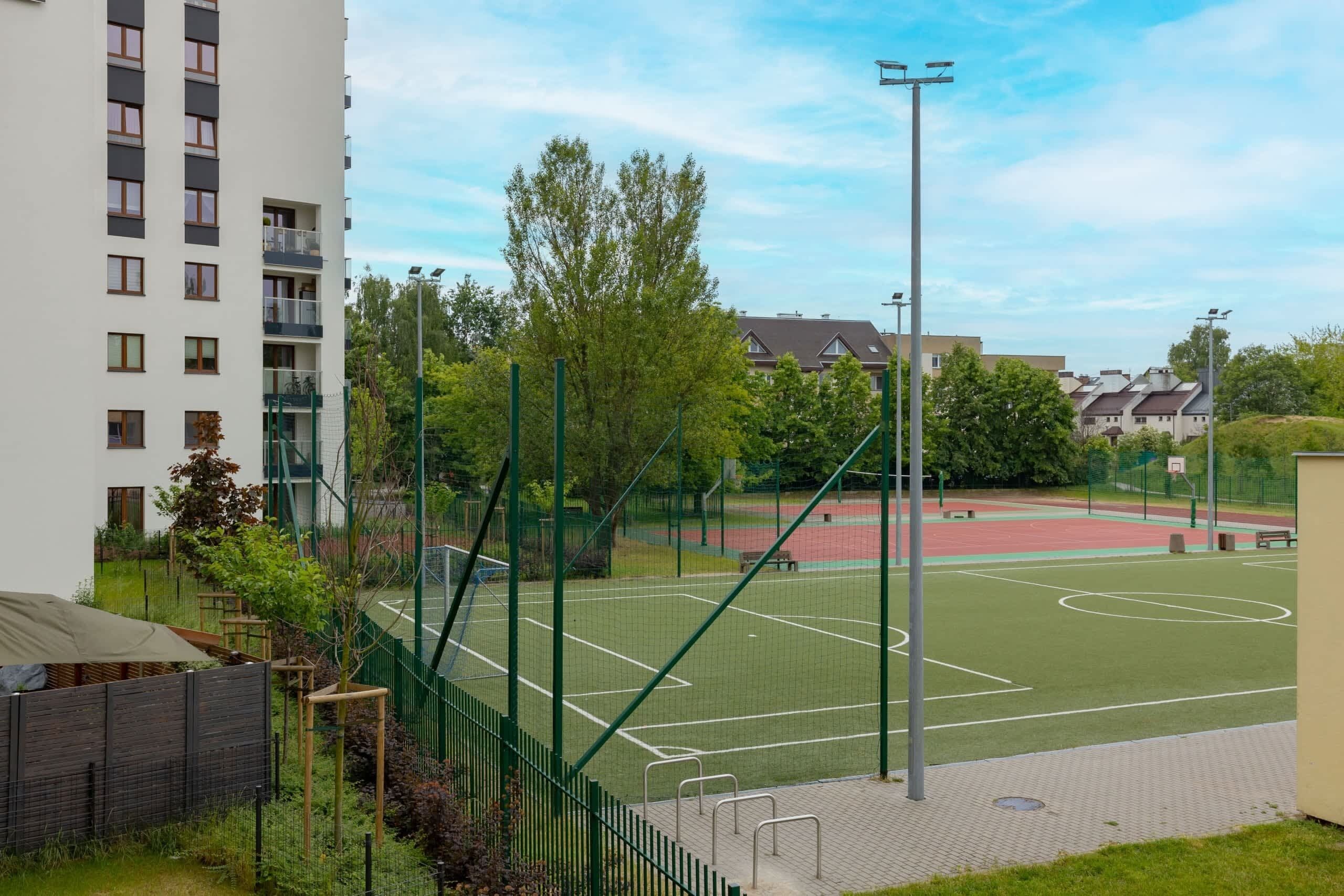 Ein Tennisplatz, umgeben von Grünflächen und Wohngebäuden.
