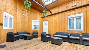 Une terrasse en bois avec des sièges d’extérieur et une porte.