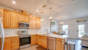 A modern kitchen with wooden cabinets, stainless steel appliances, and pendant lighting. - Seabreeze -Walk to beach! Pet friendly! (Panama City Beach)