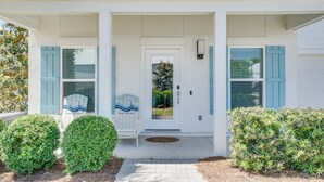 A white house with blue shutters, a front porch, and a small white chair. - Seabreeze -Walk to beach! Pet friendly! (Panama City Beach)