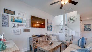 A cozy living room with a wooden coffee table, a sofa, and a staircase leading to another level. - Seabreeze -Walk to beach! Pet friendly! (Panama City Beach)
