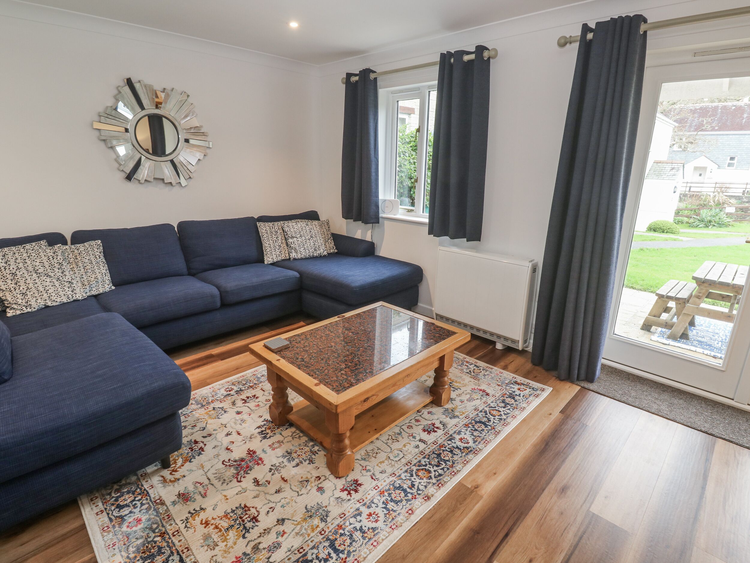 A living room with a dark blue sofa, a wooden coffee table, and a patterned rug.