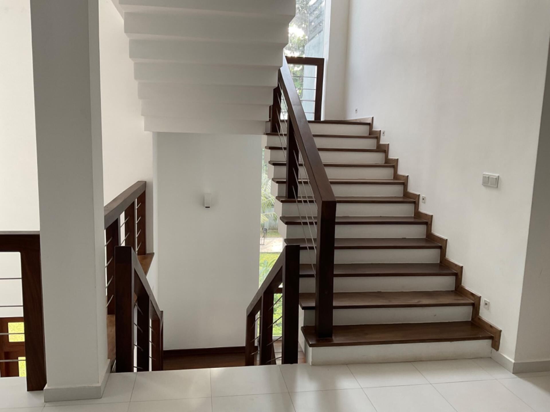 Uma escadaria com degraus de madeira e corrimão de metal, levando a um andar superior.