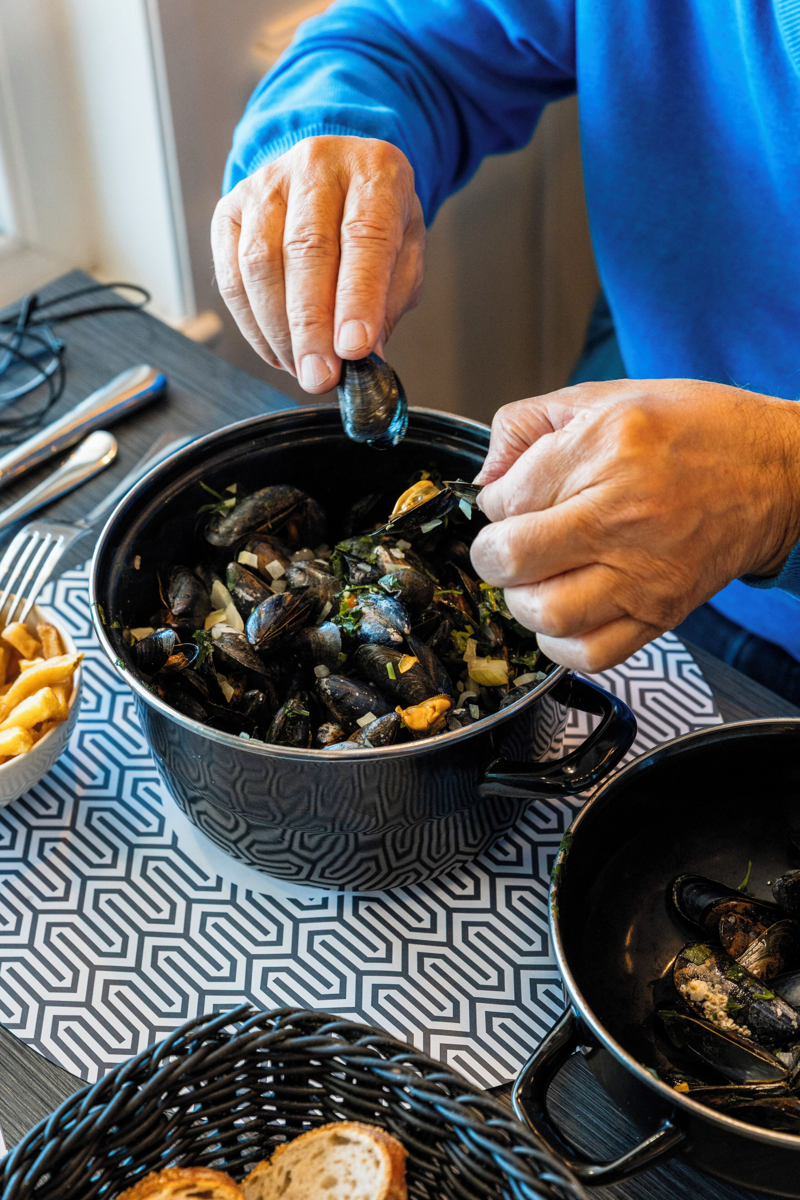A person serving mussels from a pot.