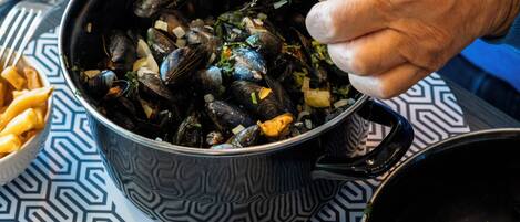 A person serving mussels from a pot.