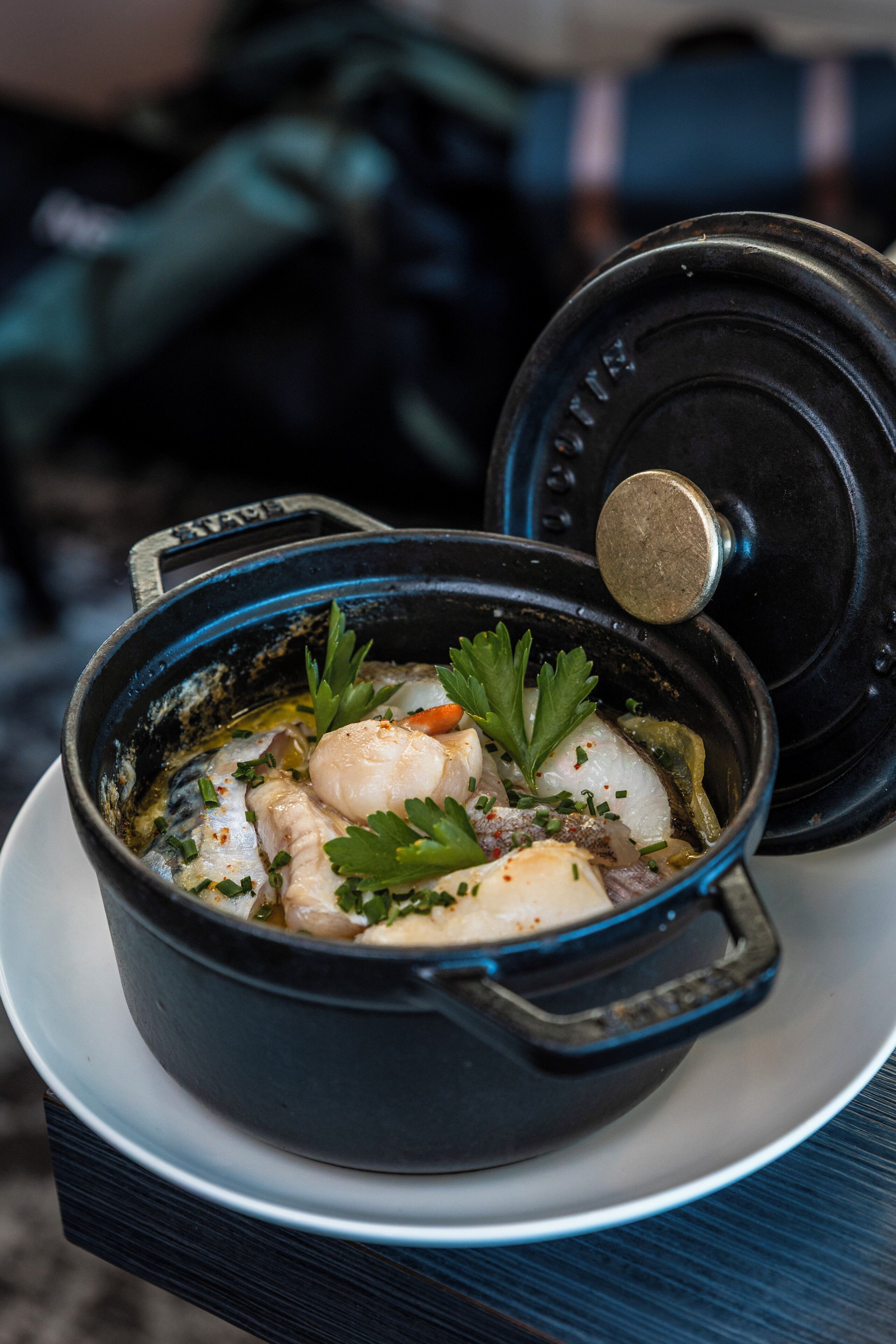 A bowl of seafood soup with a lid on a plate.