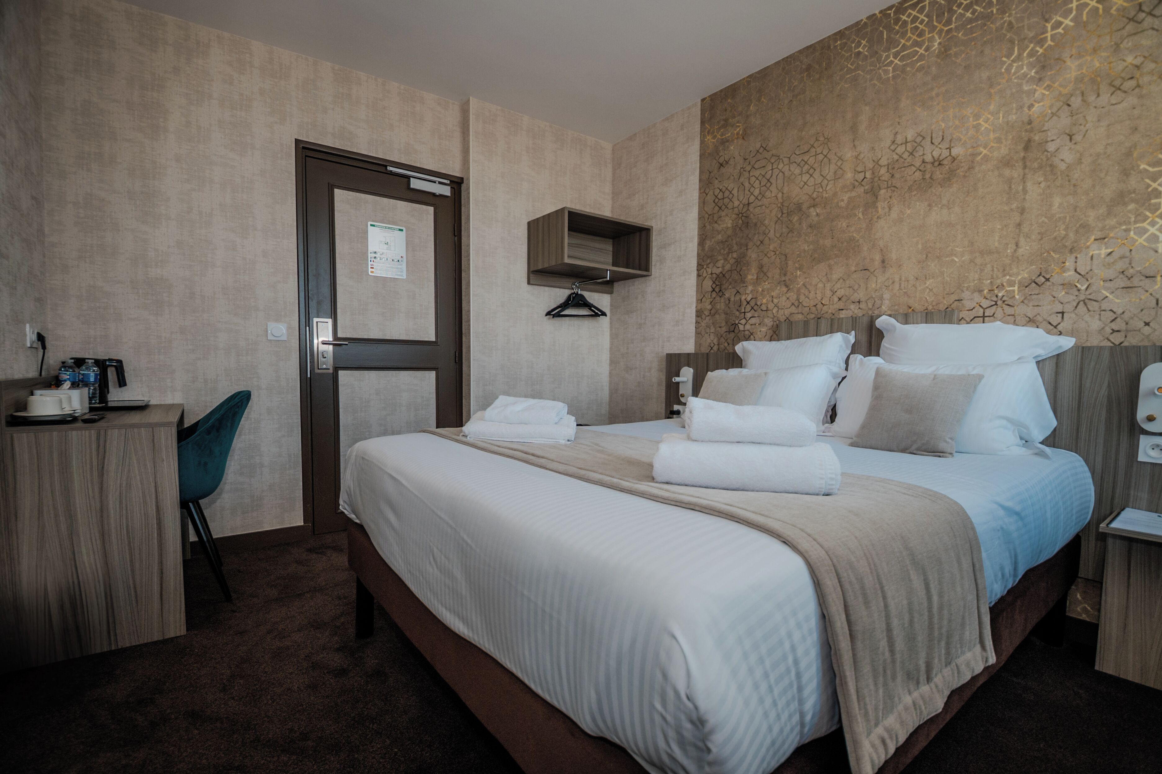 Ein Hotelzimmer mit Bett, Schreibtisch, Stuhl und Kleiderschrank.