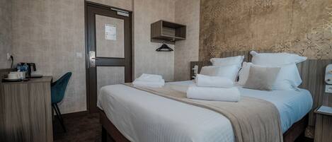 Ein Hotelzimmer mit Bett, Schreibtisch, Stuhl und Kleiderschrank.