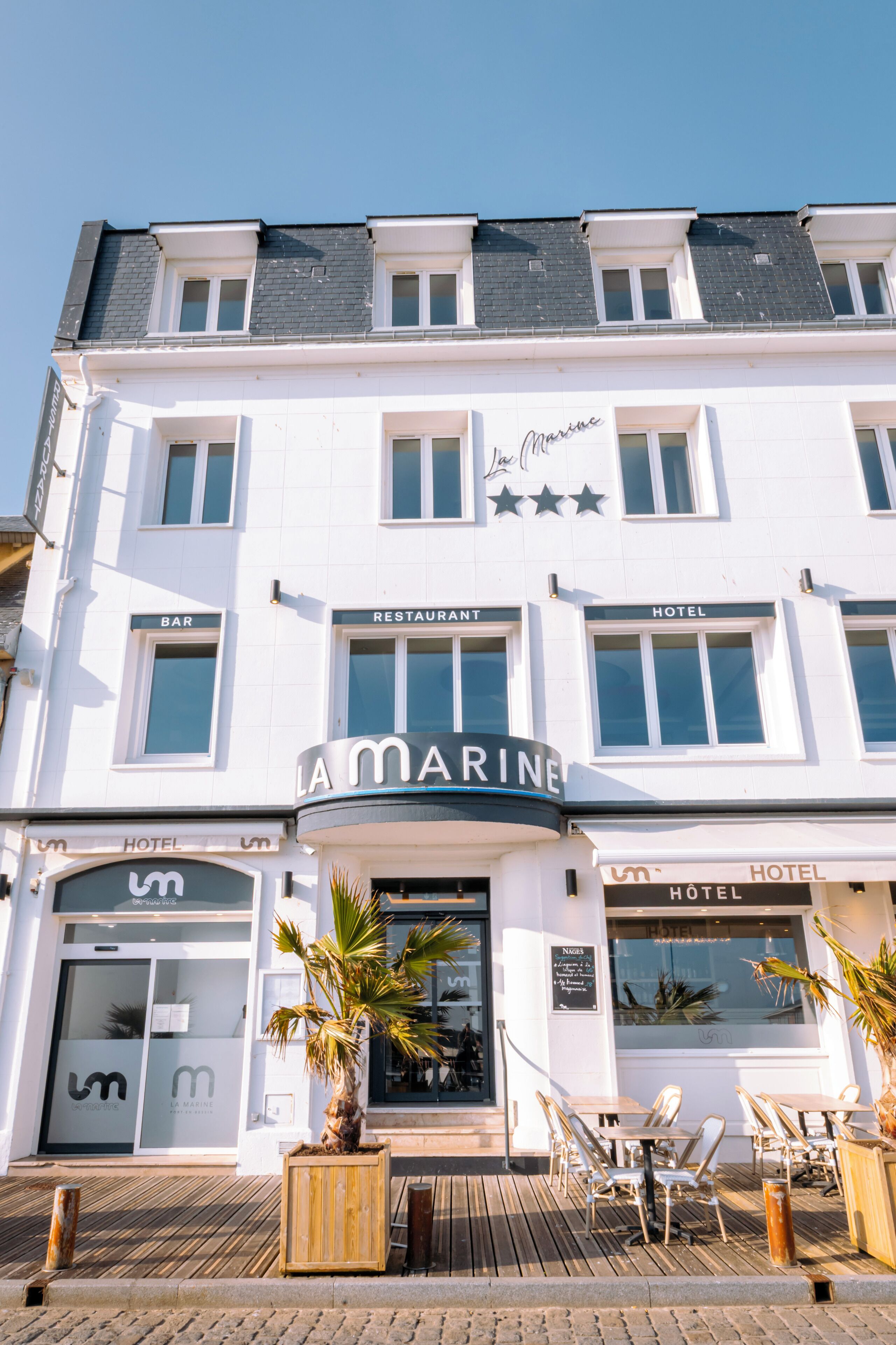 Un edificio de varios pisos con un letrero que dice "La Marine", indicando un restaurante y un hotel.