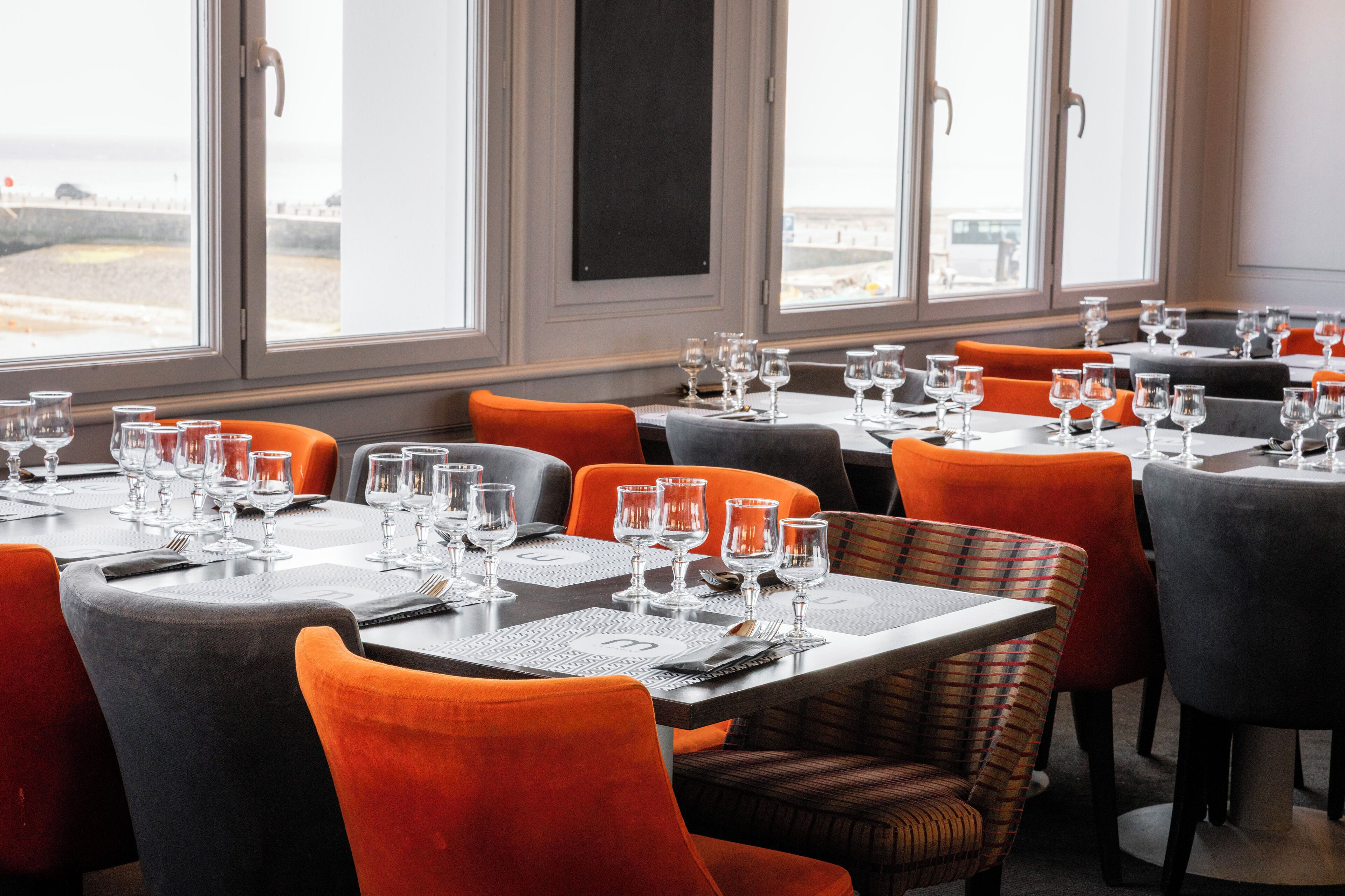 Un restaurante con mesas dispuestas para comer, que ofrece vista al mar a través de amplios ventanales.