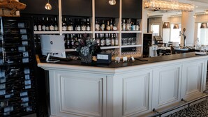 A bar area with shelves of bottles and glasses, a cash register, and a decorative fish sculpture.