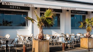 A hotel and restaurant with outdoor seating, wooden planters, and a clear view of the building's facade.