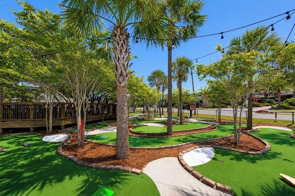 A landscaped area with trees, a winding path, and a green artificial turf surface.