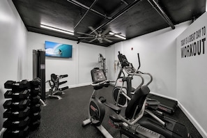 A gym with exercise equipment, a television, and motivational wall text. - Okaloosa Island Gulf Front Paradise Studio Condo (Fort Walton Beach)
